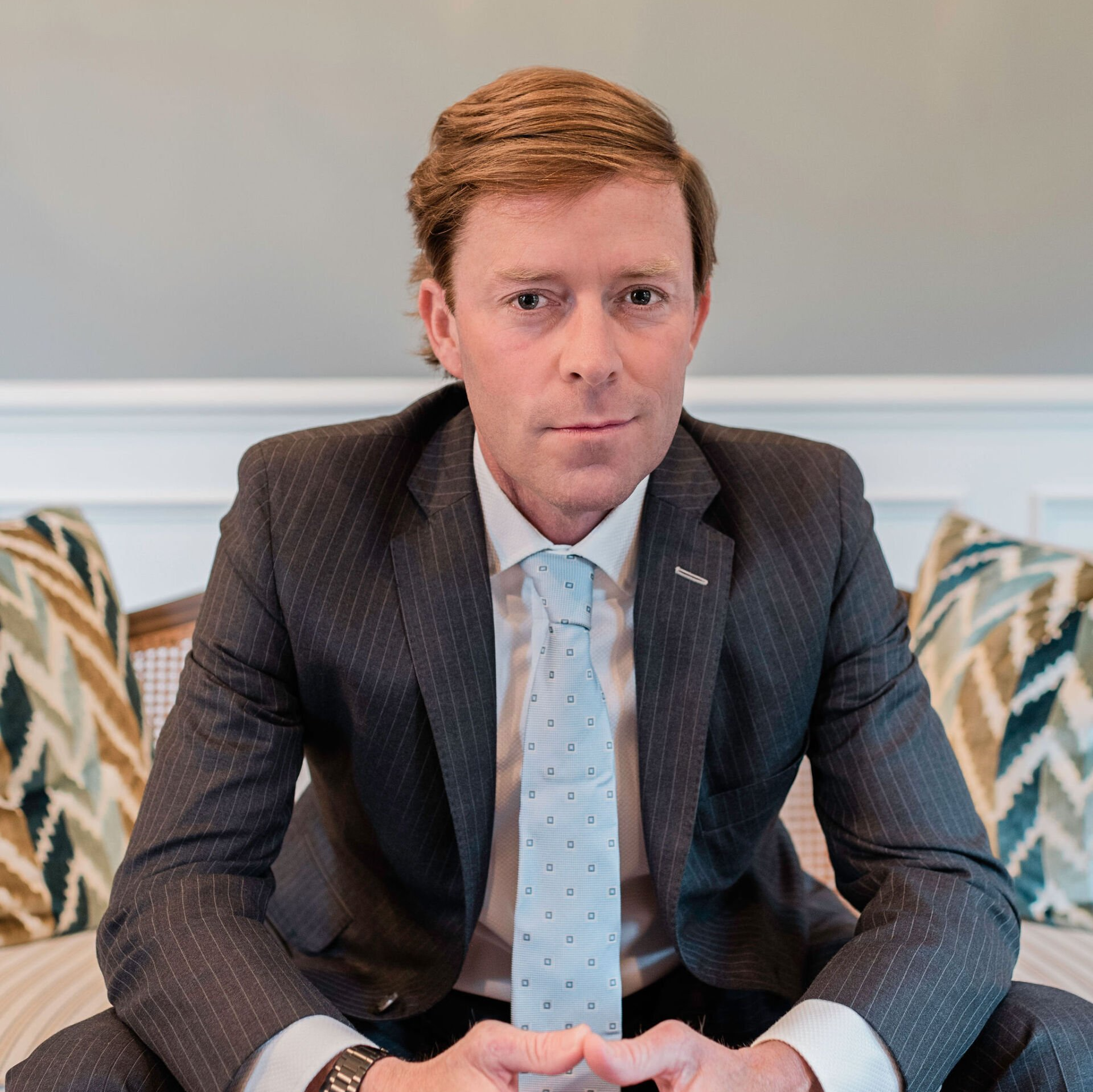 Male Personal Injury Lawyer in a suit and tie is sitting on a couch.