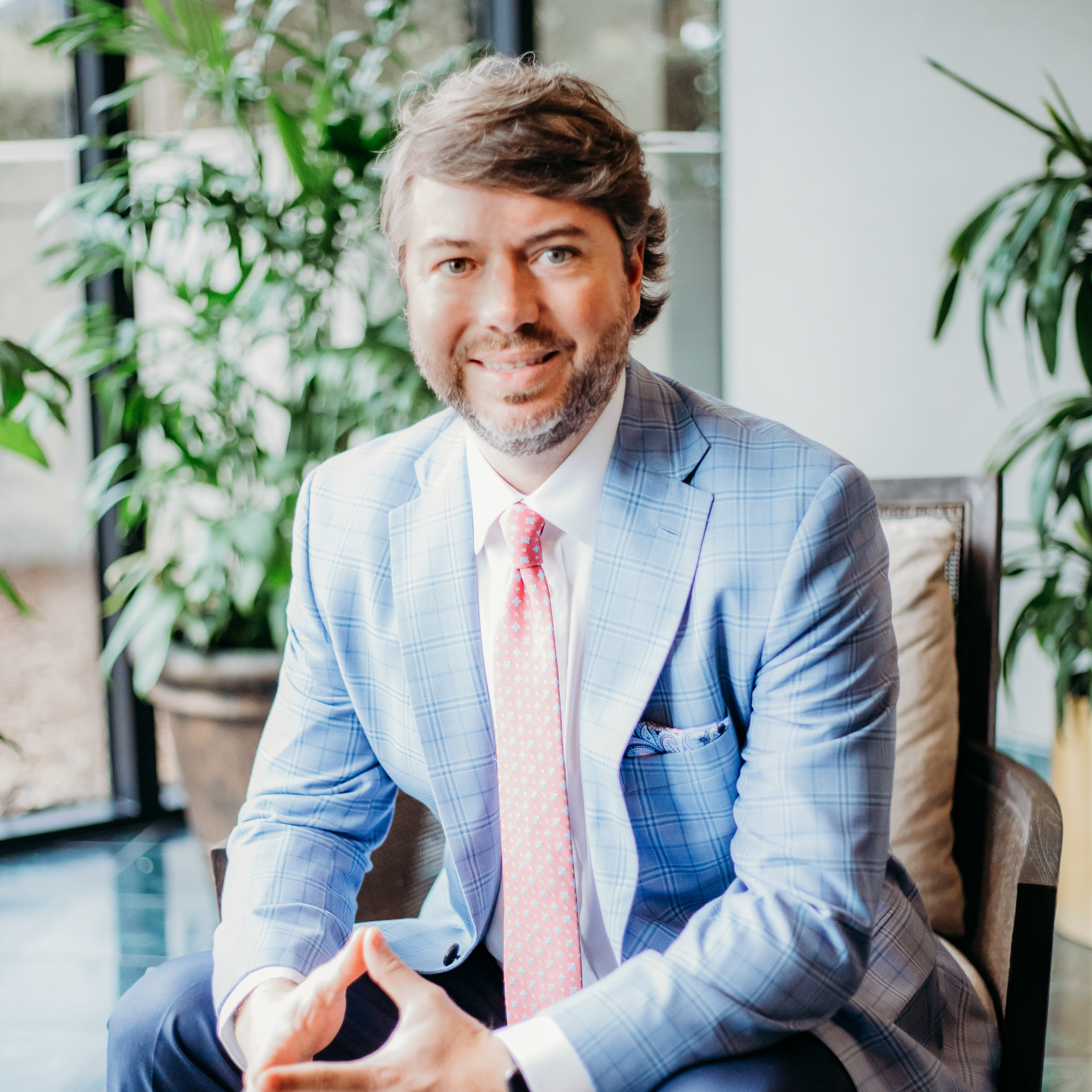 Male personal injury lawyer in a suit and tie is sitting in a chair.