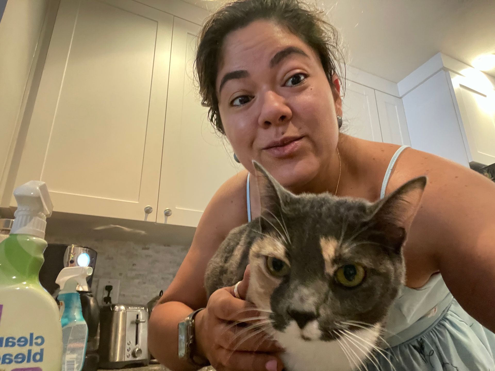 A woman is holding a cat in her arms in a kitchen.