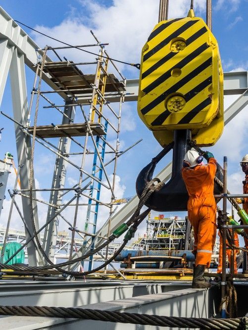 Crane Hook Lowered Toward Worker in Orange Jumpsuit on a Construction — Statewide Lift & Shift Pty Ltd In Paget, QLD