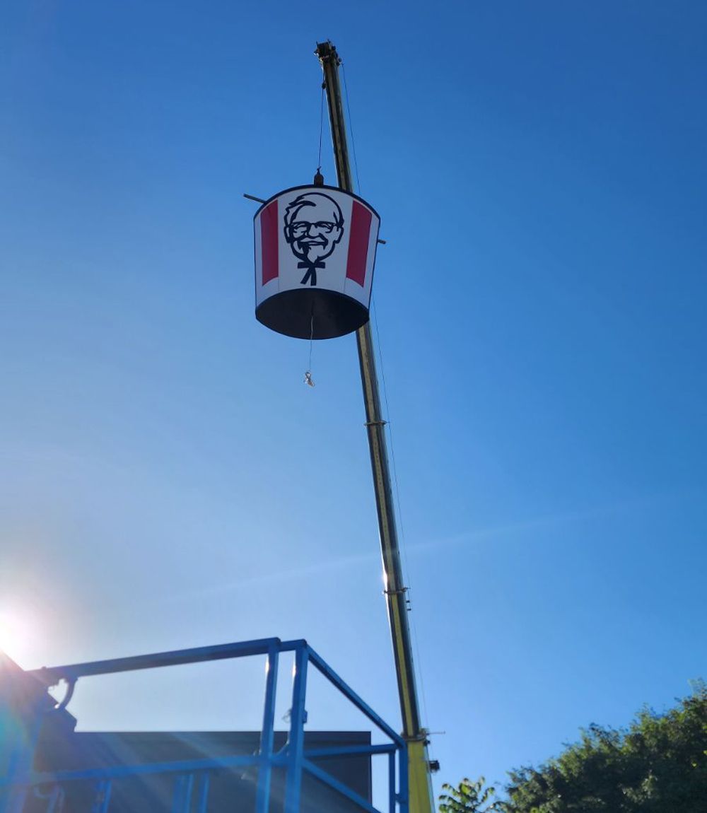 A Large Kfc Bucket is Suspended From a Crane Against a Clear, Blue Sky — Statewide Lift & Shift Pty Ltd In Paget, QLD
