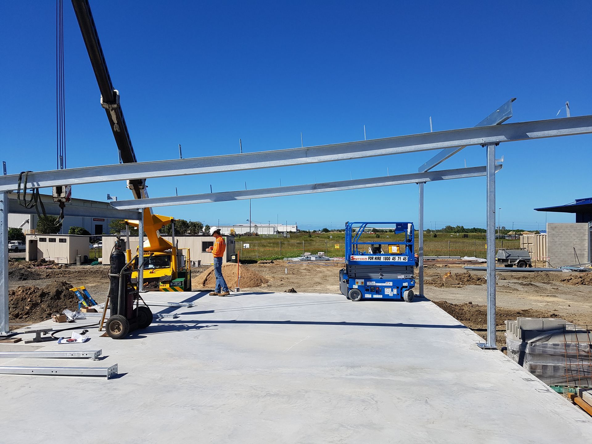 Construction site with steel framework being assembled on a concrete slab; workers and machinery present — Statewide Lift & Shift Pty Ltd In Paget, QLD
