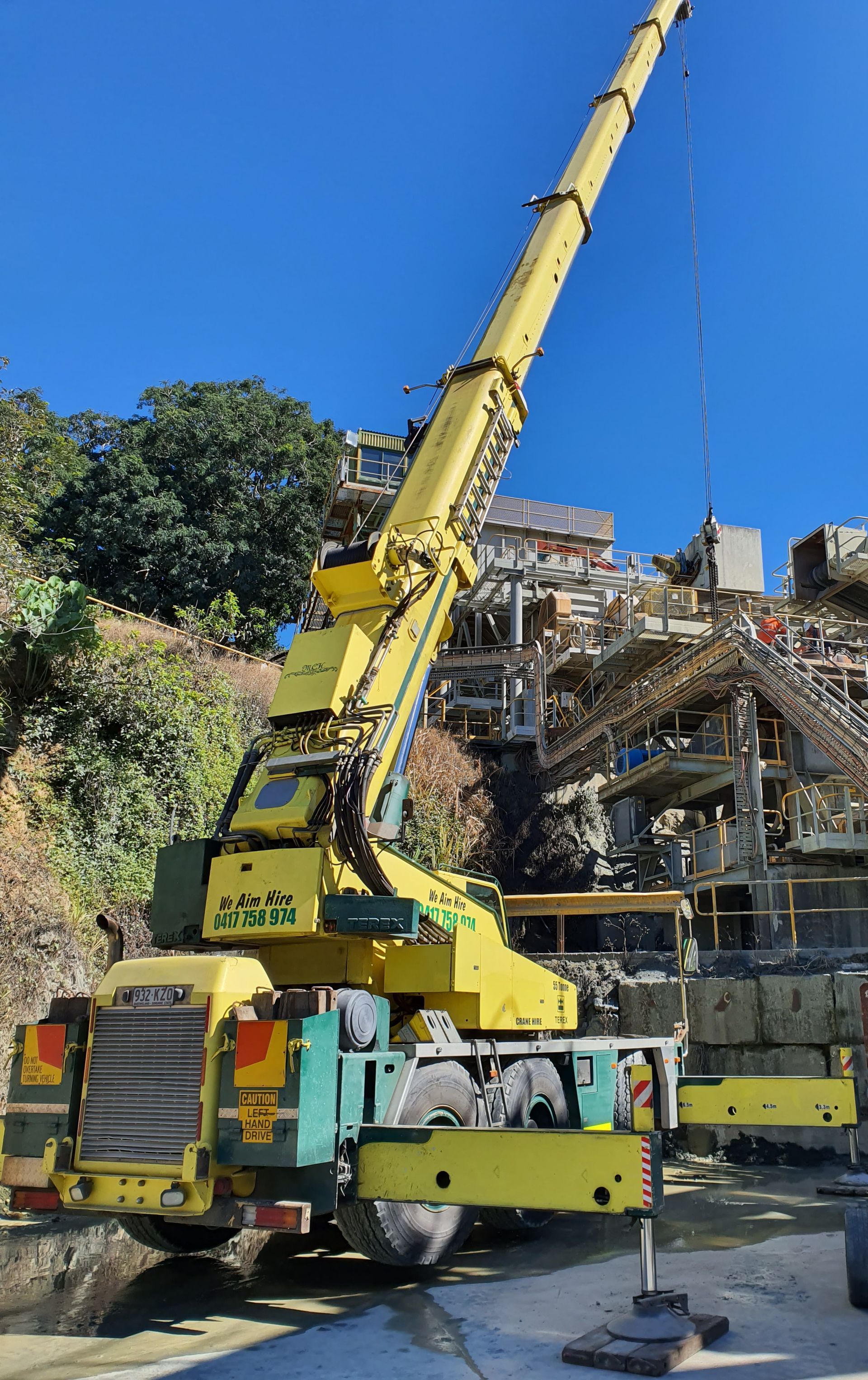 Yellow crane at a construction site, against a hillside with buildings under construction and a clear blue sky — Statewide Lift & Shift Pty Ltd In Paget, QLD
