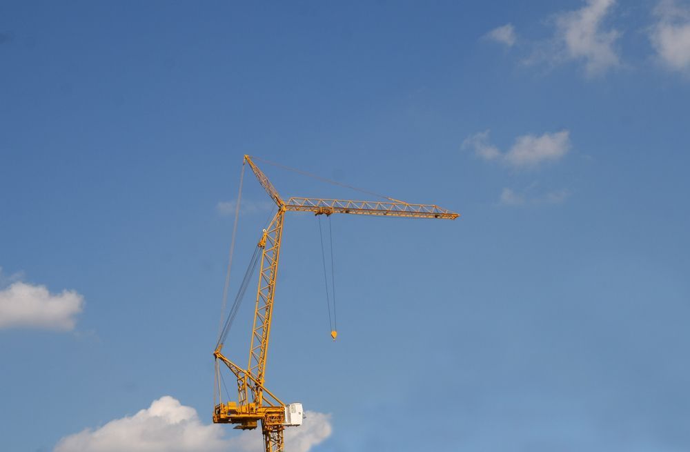 Yellow construction crane against a blue sky with white clouds — Statewide Lift & Shift Pty Ltd In Paget, QLD
