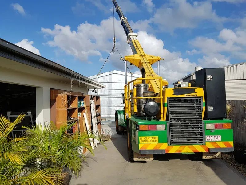 Yellow Crane Lifting Something Near a Building; Sunny Day — Statewide Lift & Shift Pty Ltd In Paget, QLD