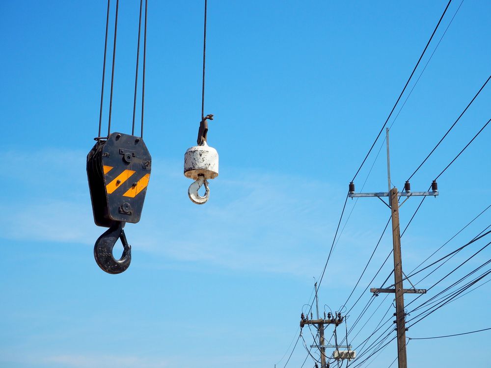 Crane Hooks Against a Bright Blue Sky, With Power Lines in the Background — Statewide Lift & Shift Pty Ltd In Nebo, QLD