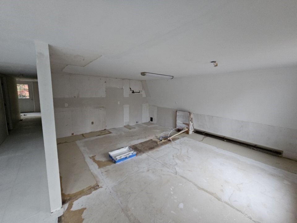 Interior room under renovation, with white walls and exposed flooring.
