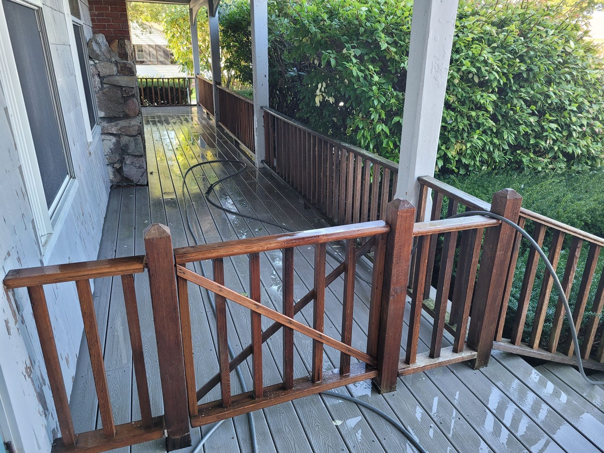 Wooden deck with railing being cleaned with water.