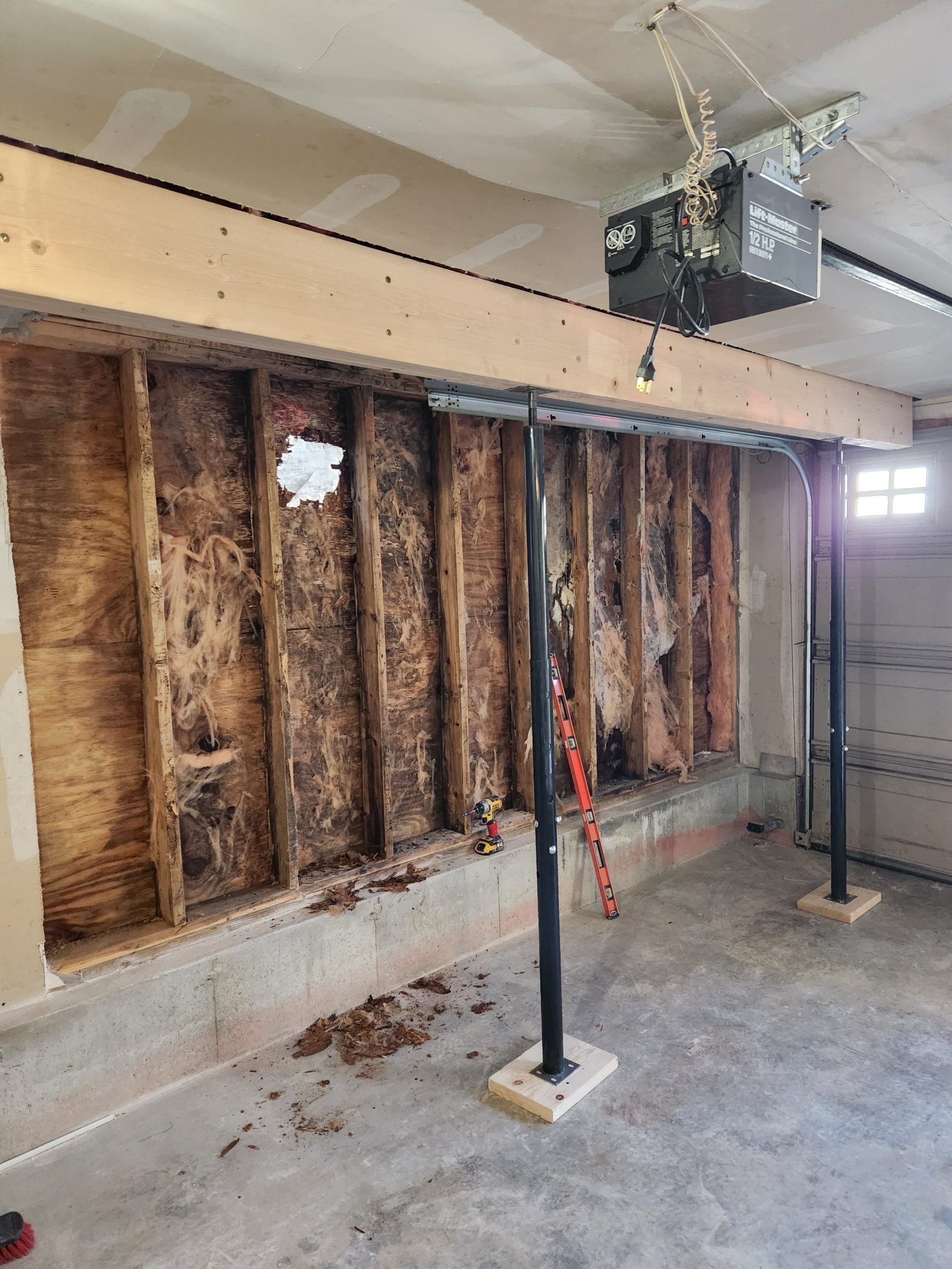 Garage wall with exposed insulation and support beams. Garage door opener visible.