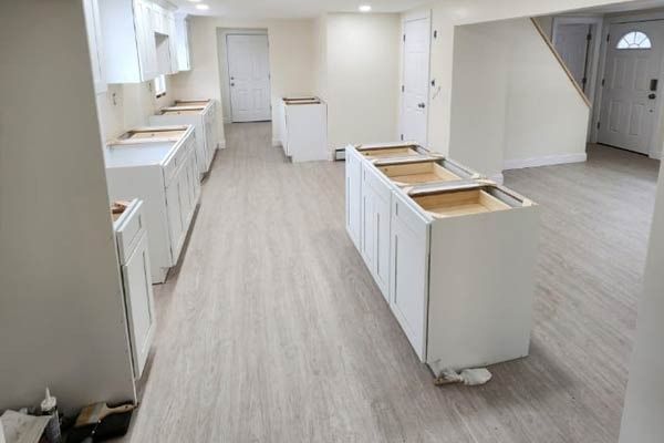 Newly installed white kitchen cabinets in a room with light wood-look flooring.
