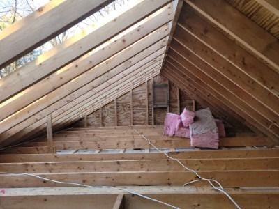 Interior attic framing with exposed wooden beams and pink insulation.