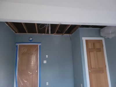 Room with exposed ceiling beams and two wooden doors, blue walls.