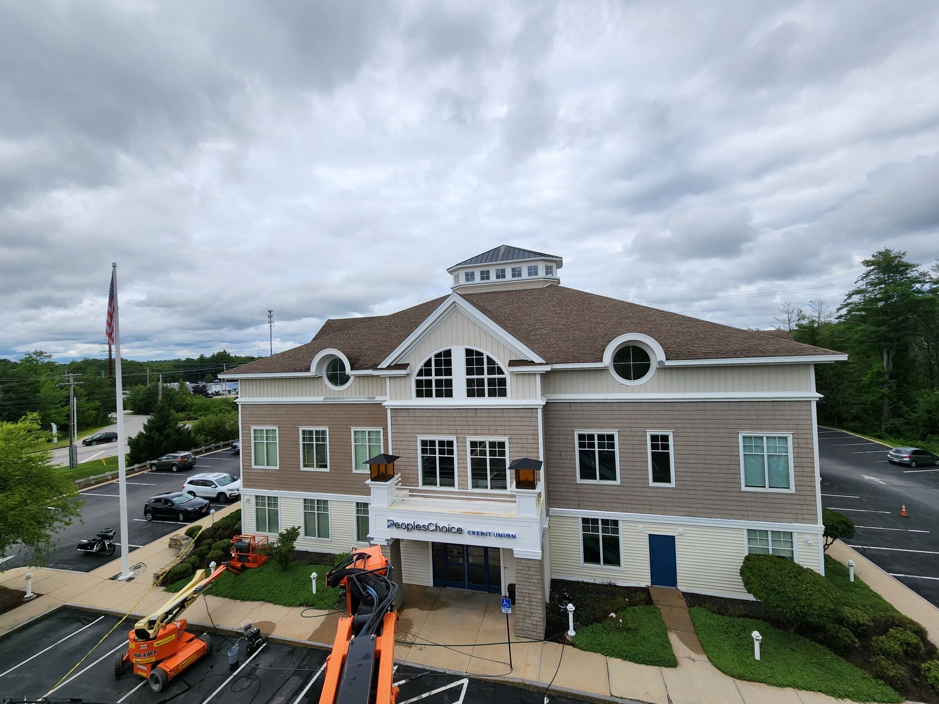 Office building with American flag, cloudy sky, and orange lift.