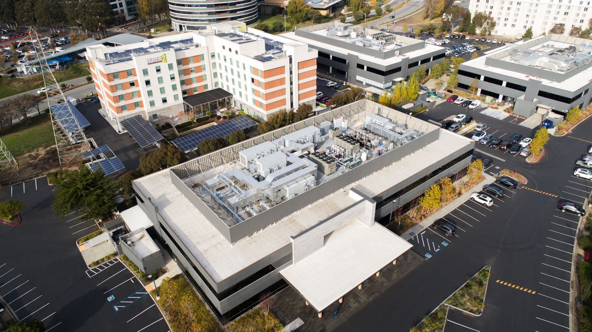 Aerial view of a modern hospital complex with parking lots and surrounding buildings.