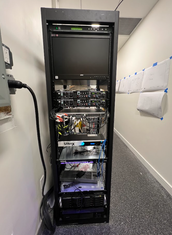 A server rack with a tv on top of it in a hallway.