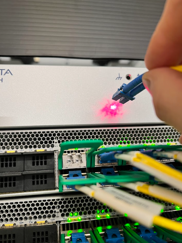 A person is plugging a fiber optic cable into a server