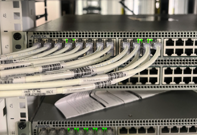 A bunch of wires are connected to a server in a server room.