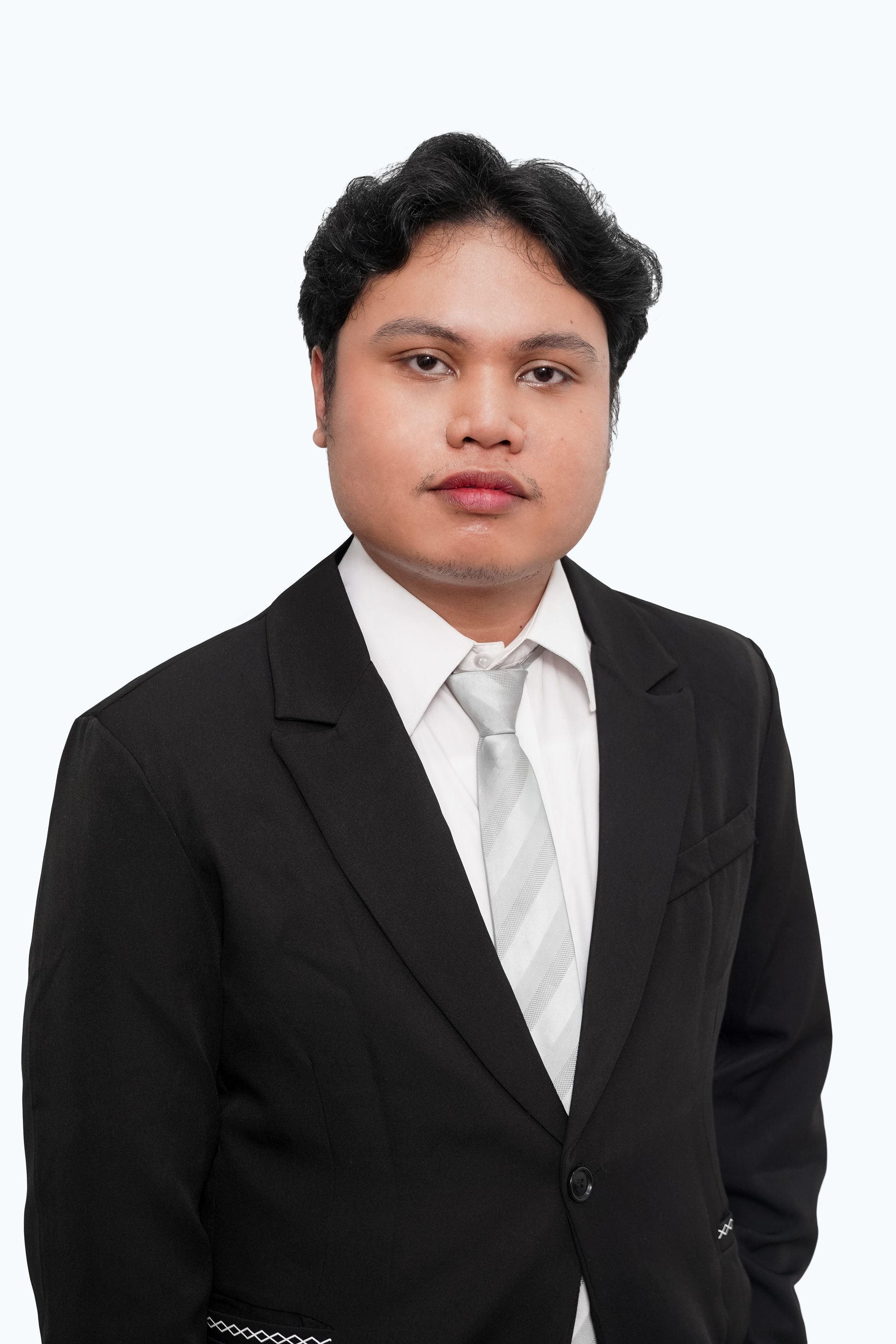 A man in a suit and tie is standing with his hands in his pockets.