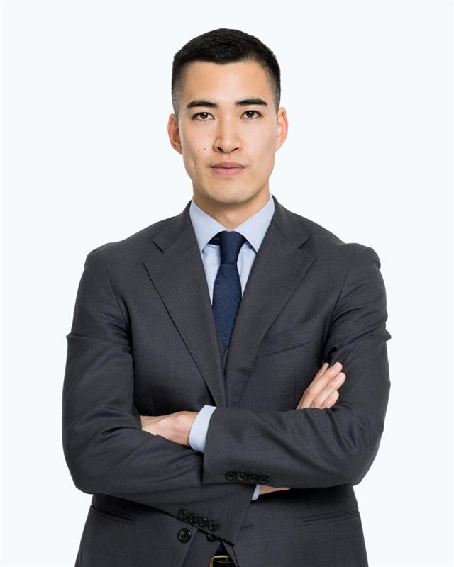 A man in a suit and tie is standing with his hands in his pockets.