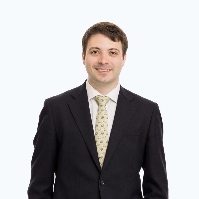 A man in a suit and tie is standing with his hands in his pockets.