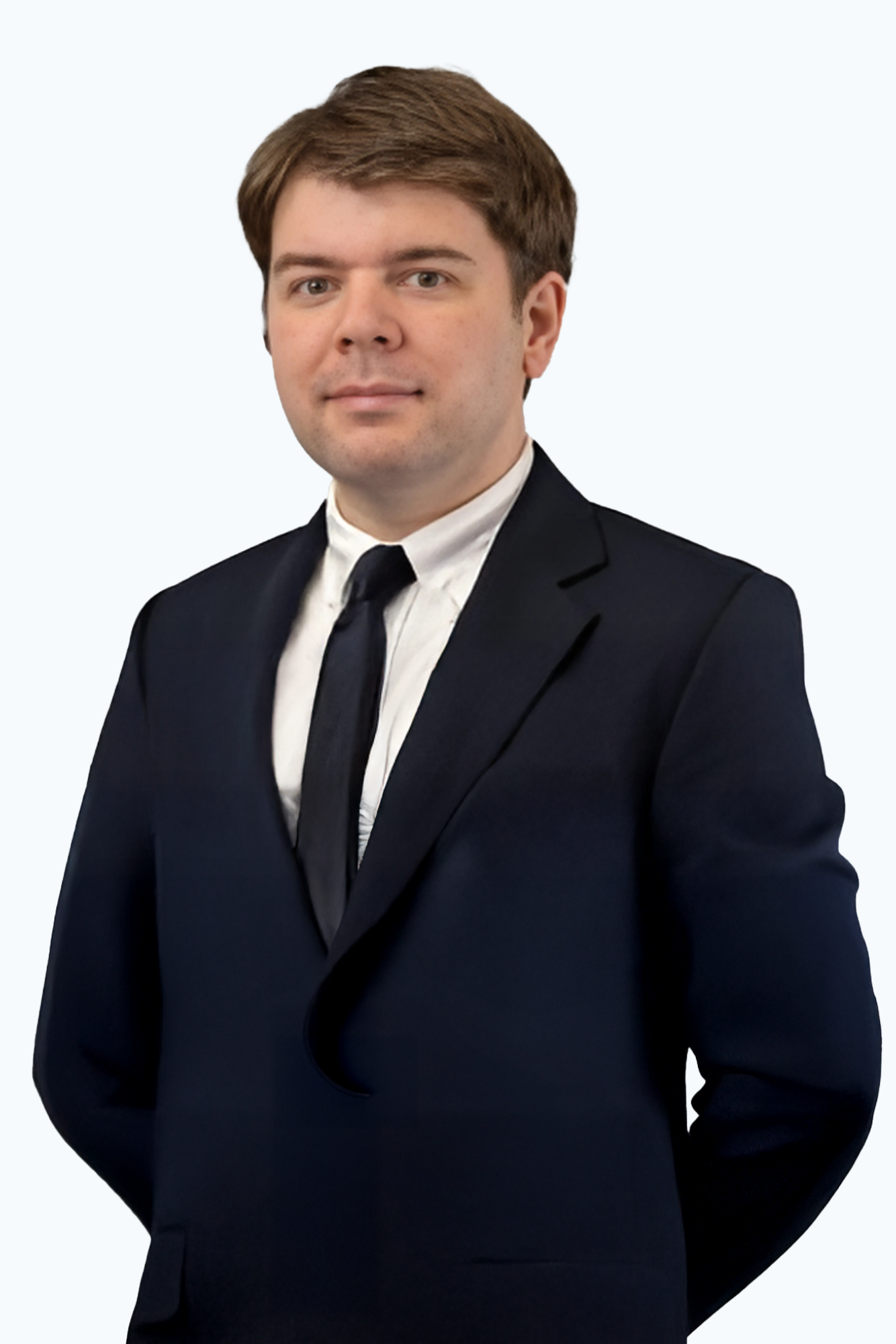 A man in a suit and tie is standing with his hands in his pockets.