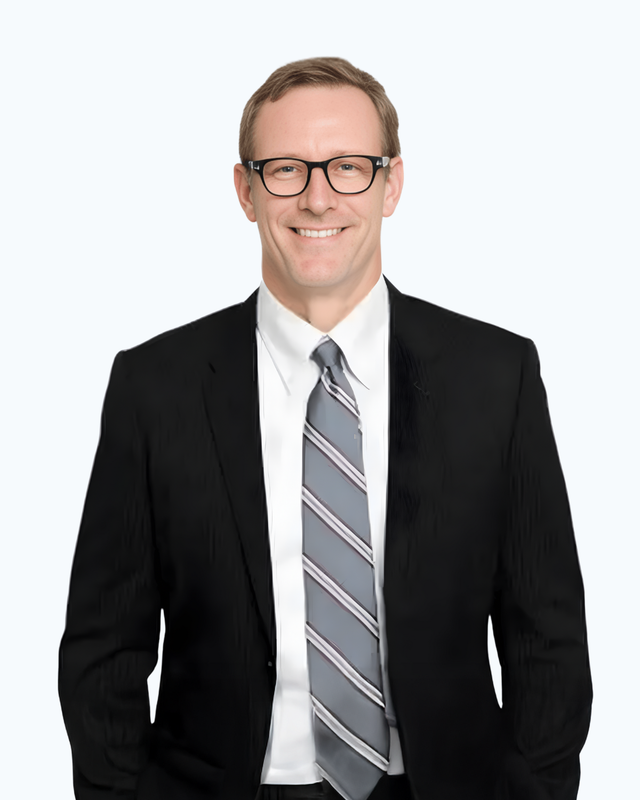 A man in a suit and tie is smiling with his hands in his pockets.
