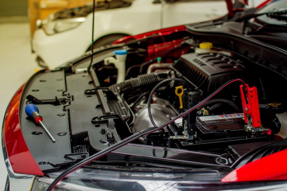 Red Car Engine Bay Open, Jumper Cables Connected to Battery — Symbiote Systems in Cannonvale, QLD