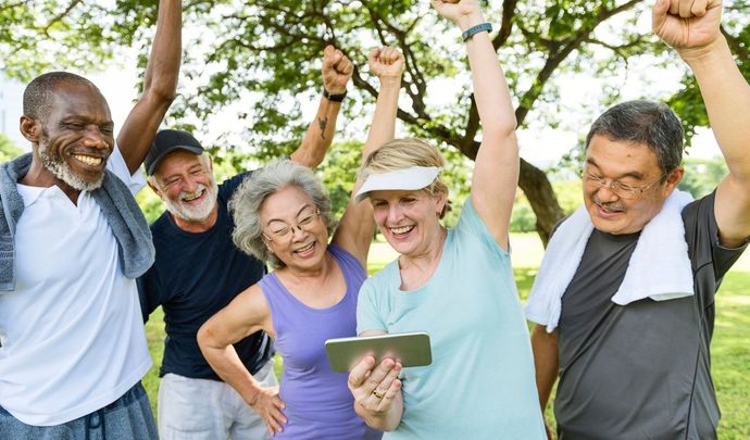 a group of elderly people are standing in a park with their hands in the air celebrating the end of their workout.