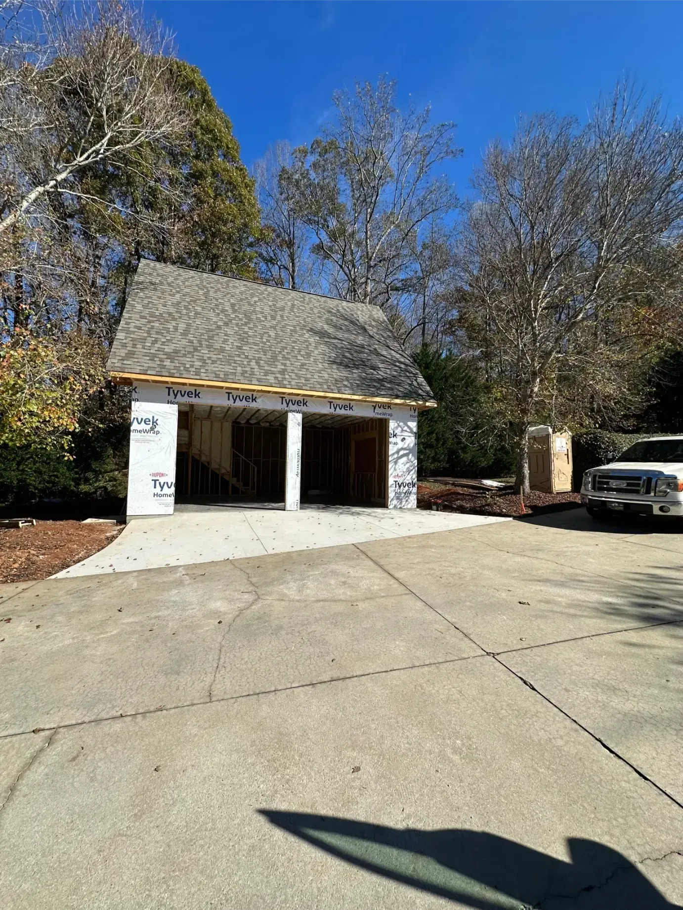 Tan and white two-car garage with vertical siding, brown trim, and a small white door.