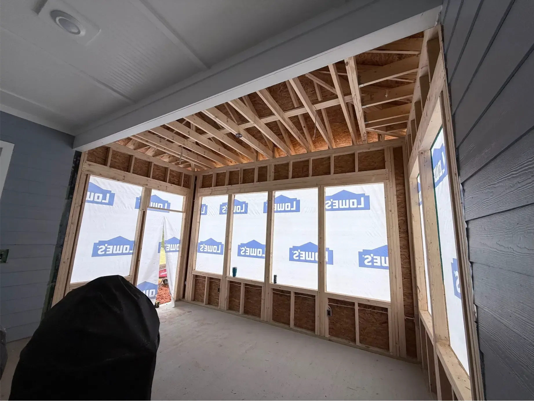 Backyard patio with fire pit, seating, grill, and lounge area, surrounded by greenery.