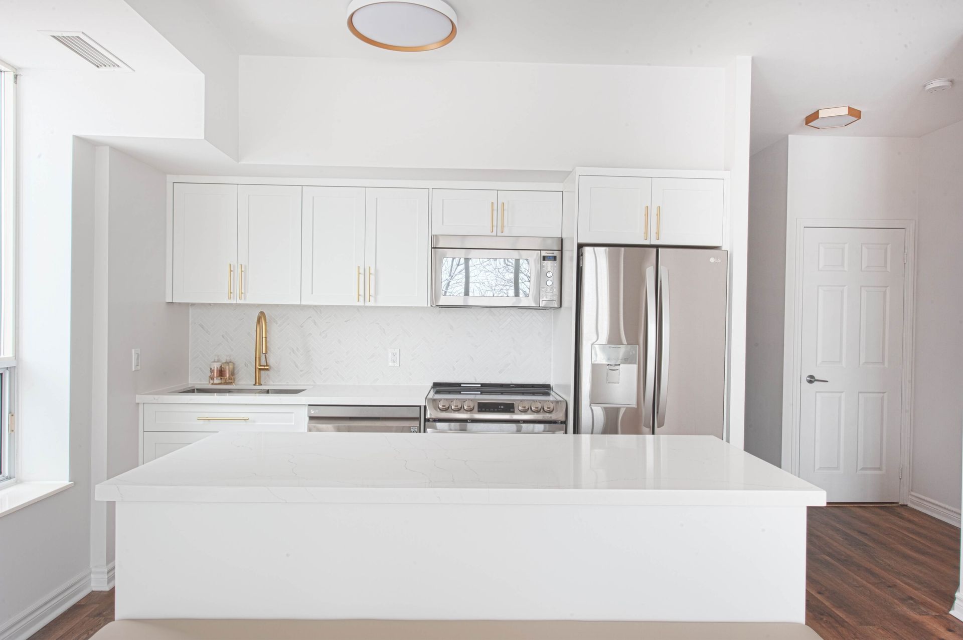 Modern white kitchen with stainless steel appliances and a center island.