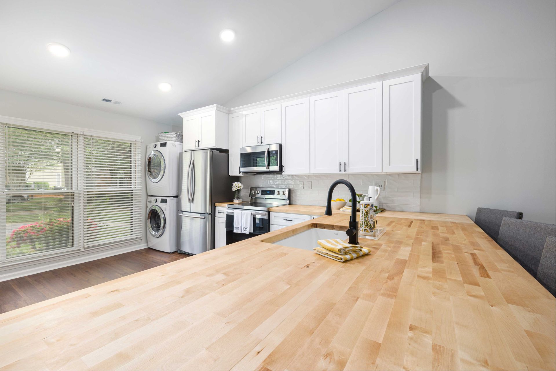Modern kitchen with white cabinets, stainless steel appliances, and a butcher block countertop.