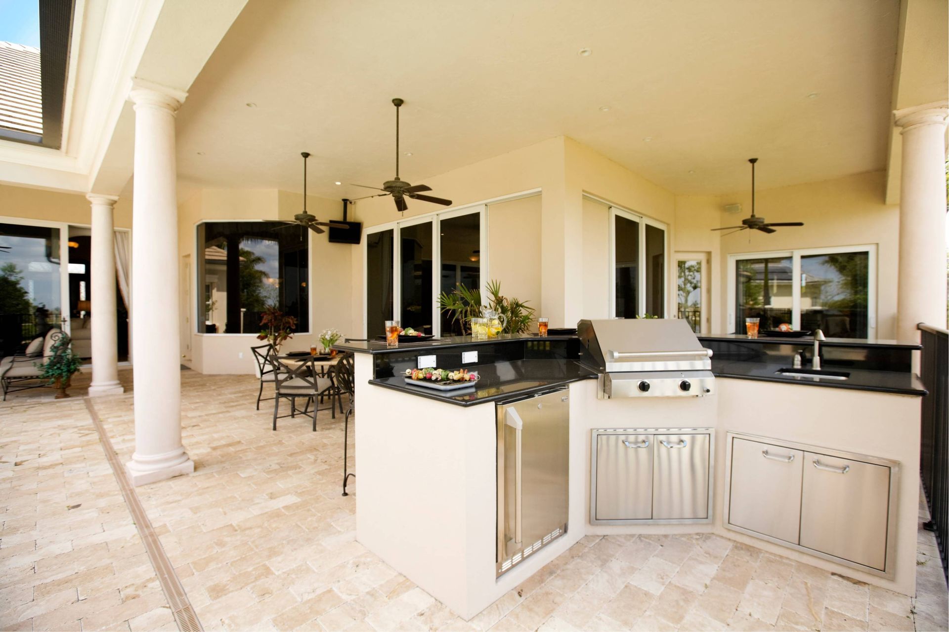 Outdoor kitchen with grill, countertop, cabinets, sink, and dining area.