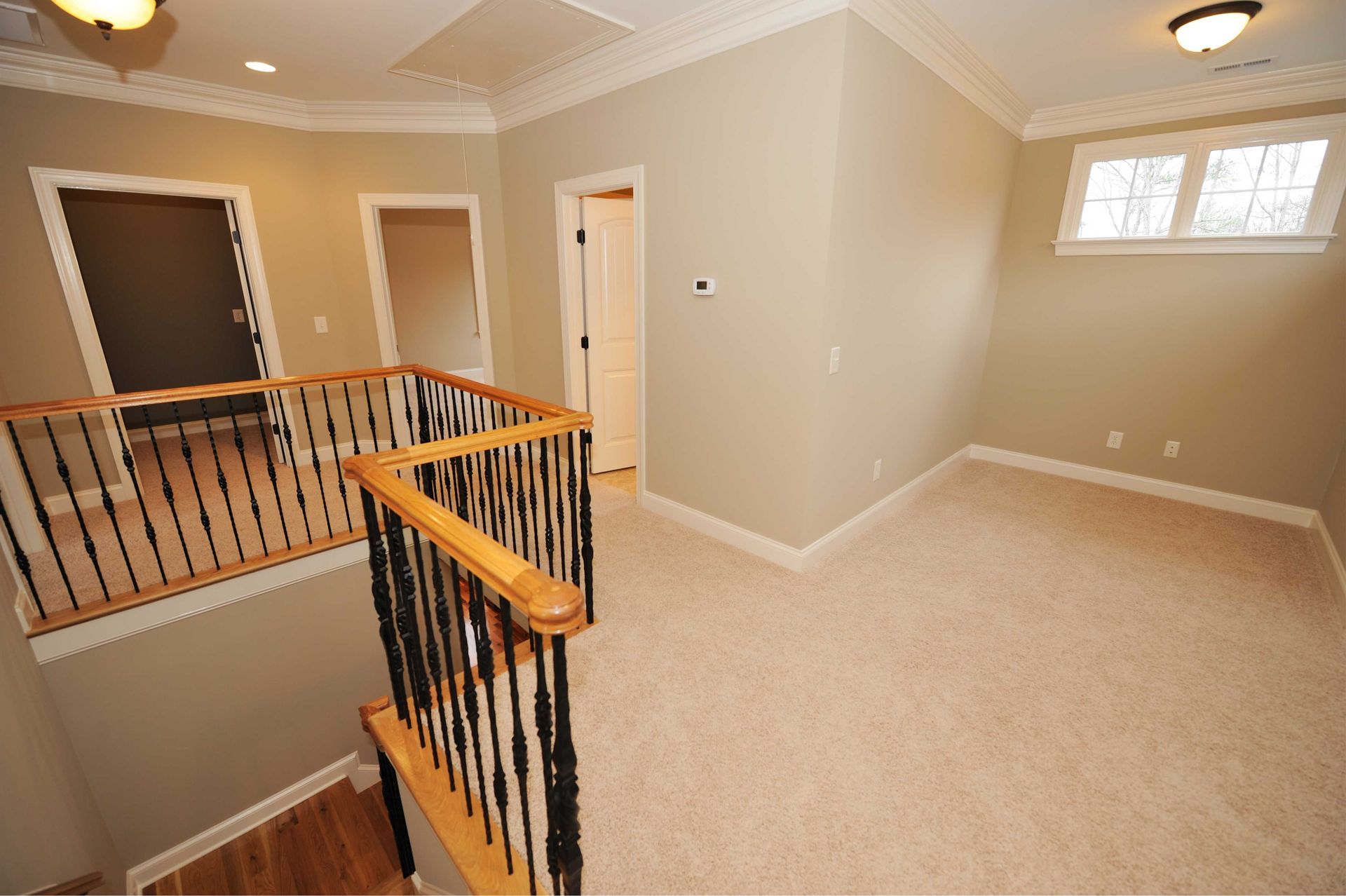 Interior second-floor landing with carpet, railing, and doors. Beige walls and cream-colored trim.