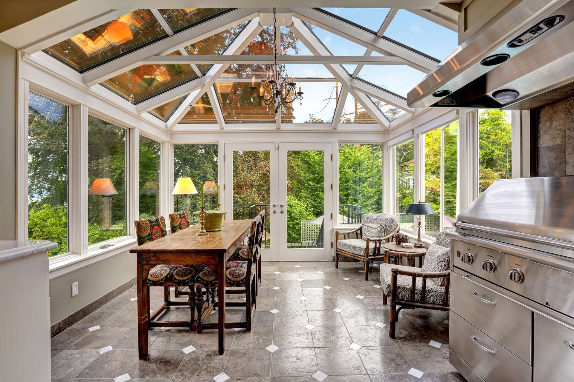 Sunroom with a glass roof, stone floor, and a dining table, chairs, and outdoor grill.