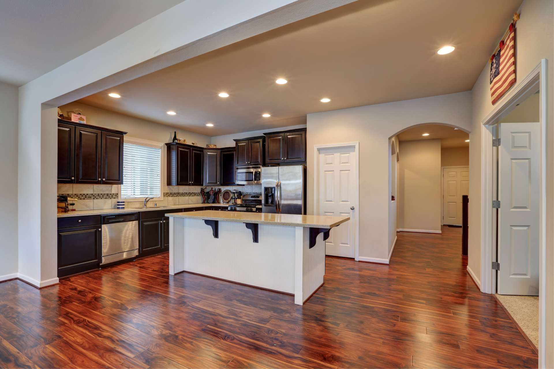 Kitchen with dark cabinets, white island, and hardwood floors.