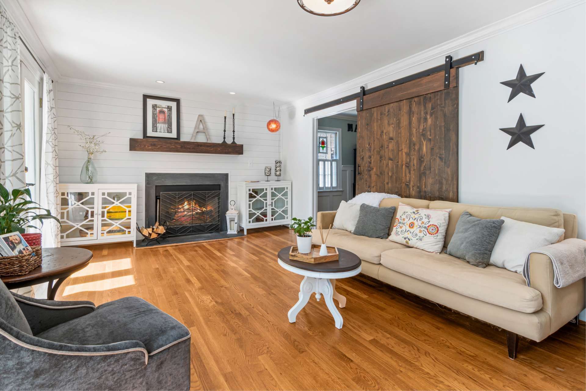 Living room with fireplace, wood floors, beige sofa, and a barn door.