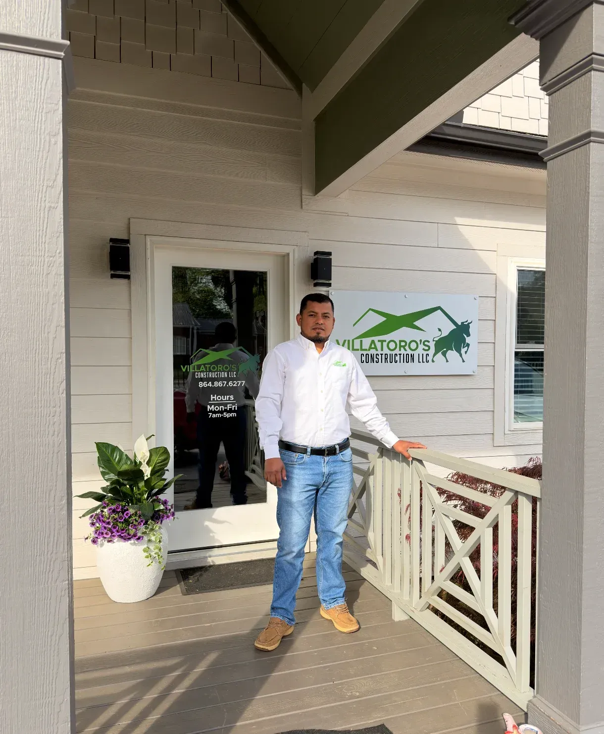 Construction worker with clipboard talking to a couple in a room with cardboard boxes and a ladder.