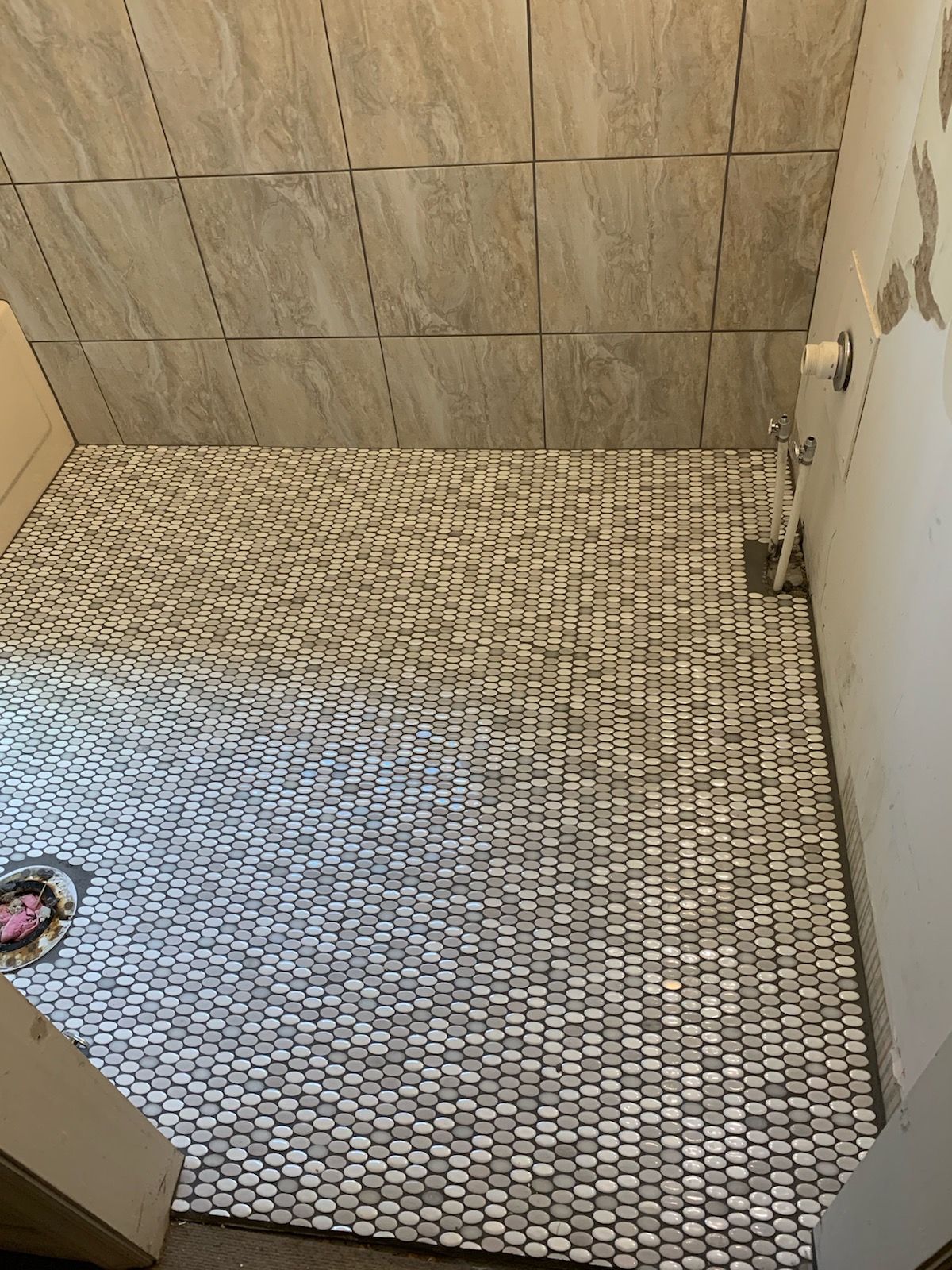 A bathroom with a tiled floor and a drain.