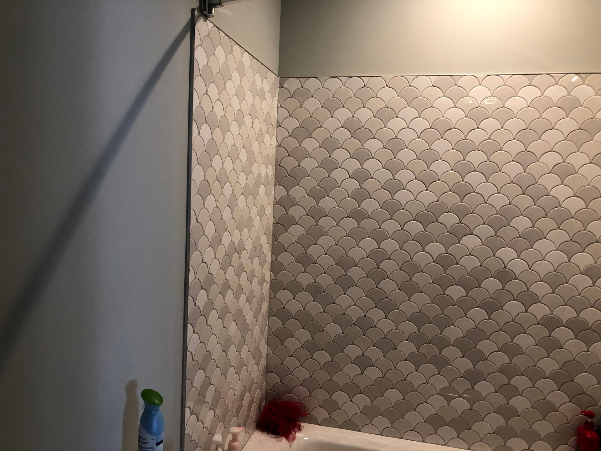 A bathroom with a tiled wall and a bathtub.