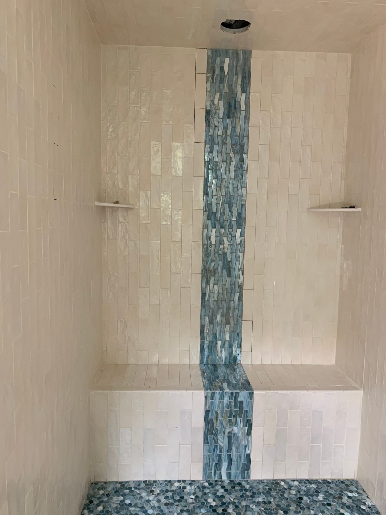 A bathroom with white tiles and a blue stripe on the wall