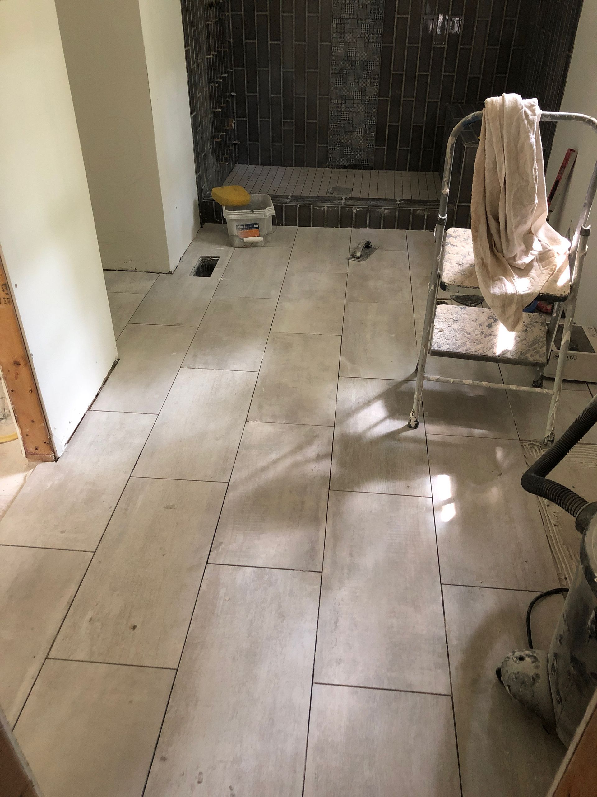 A ladder is sitting on the floor of a bathroom under construction