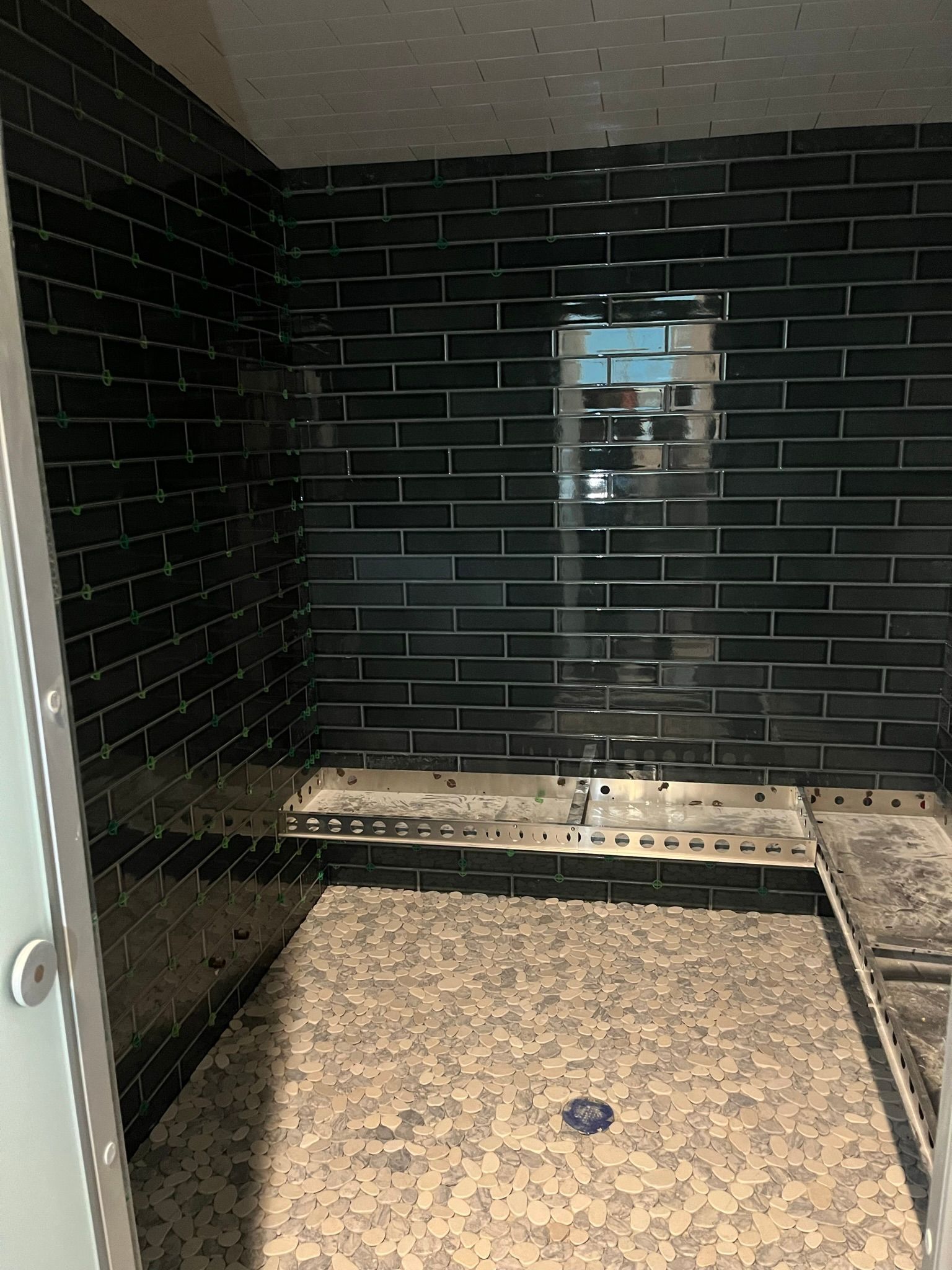 A bathroom with black brick walls and a tiled floor
