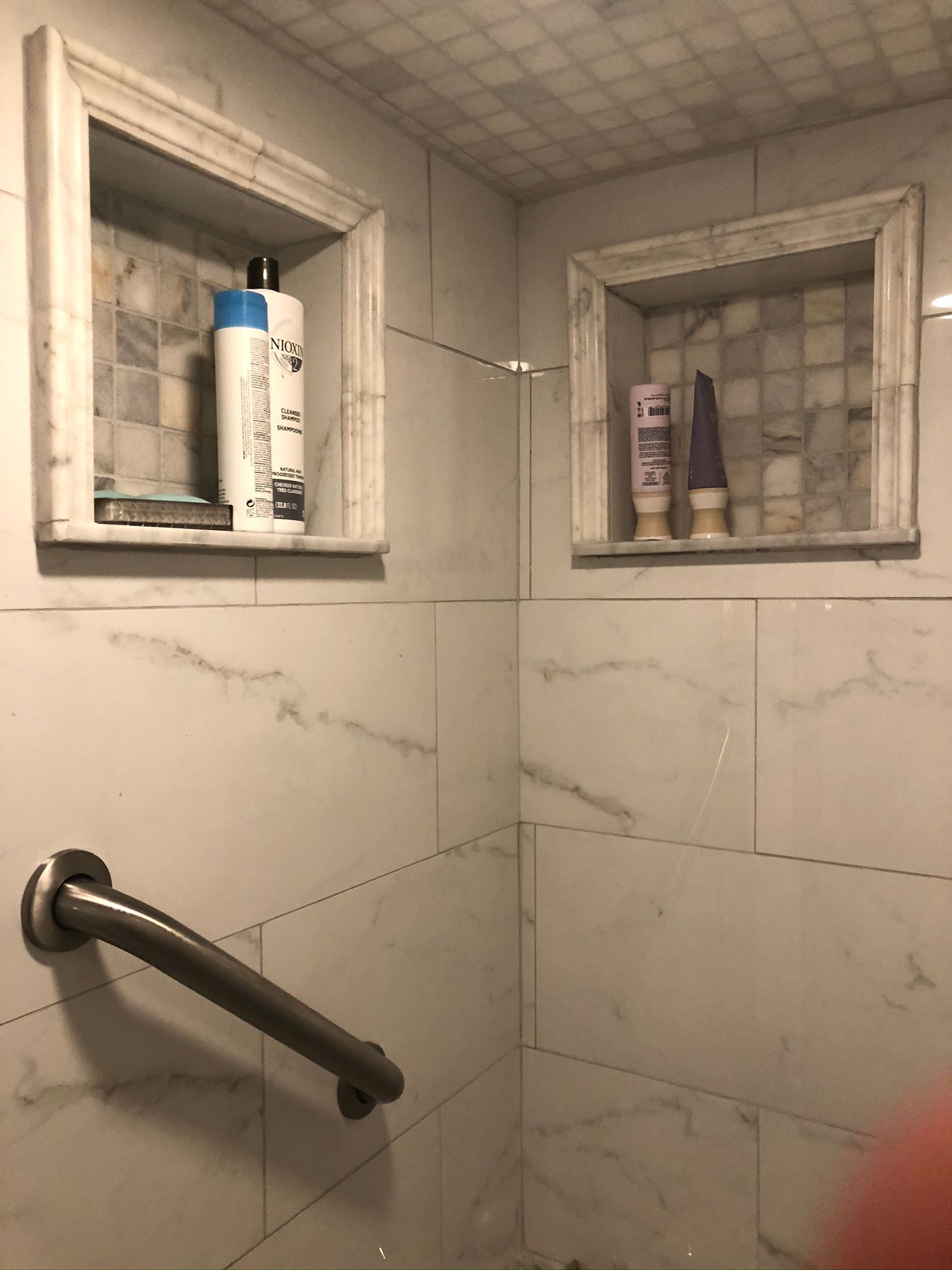 A bathroom with a shelf with shampoo and conditioner on it