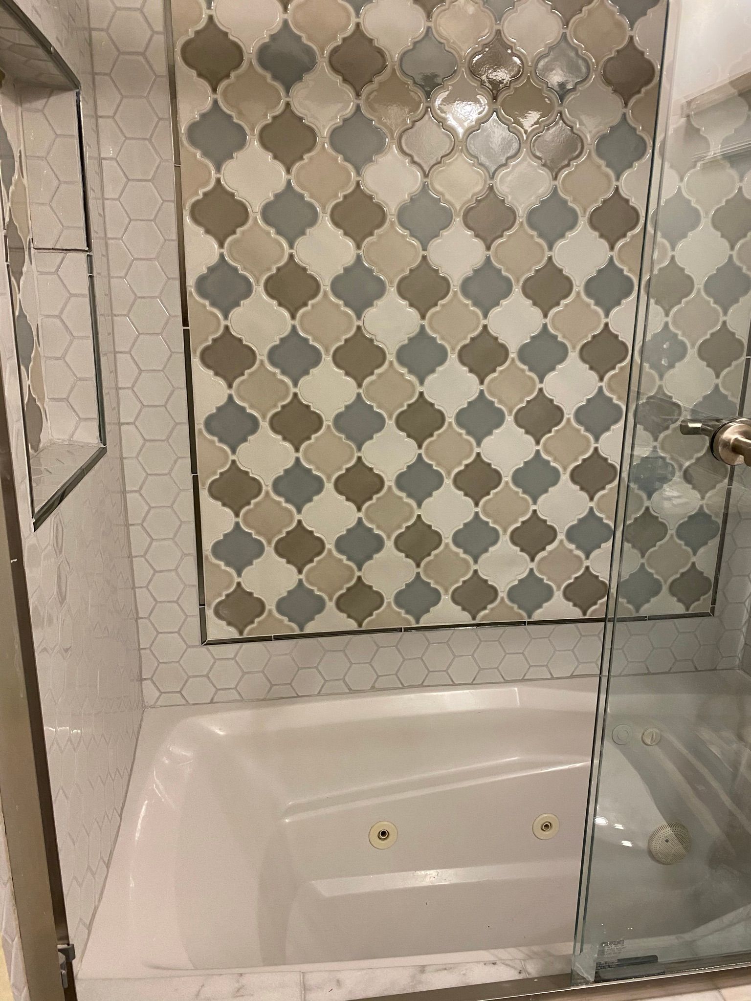 A bathroom with a bathtub and a shower with a tiled wall