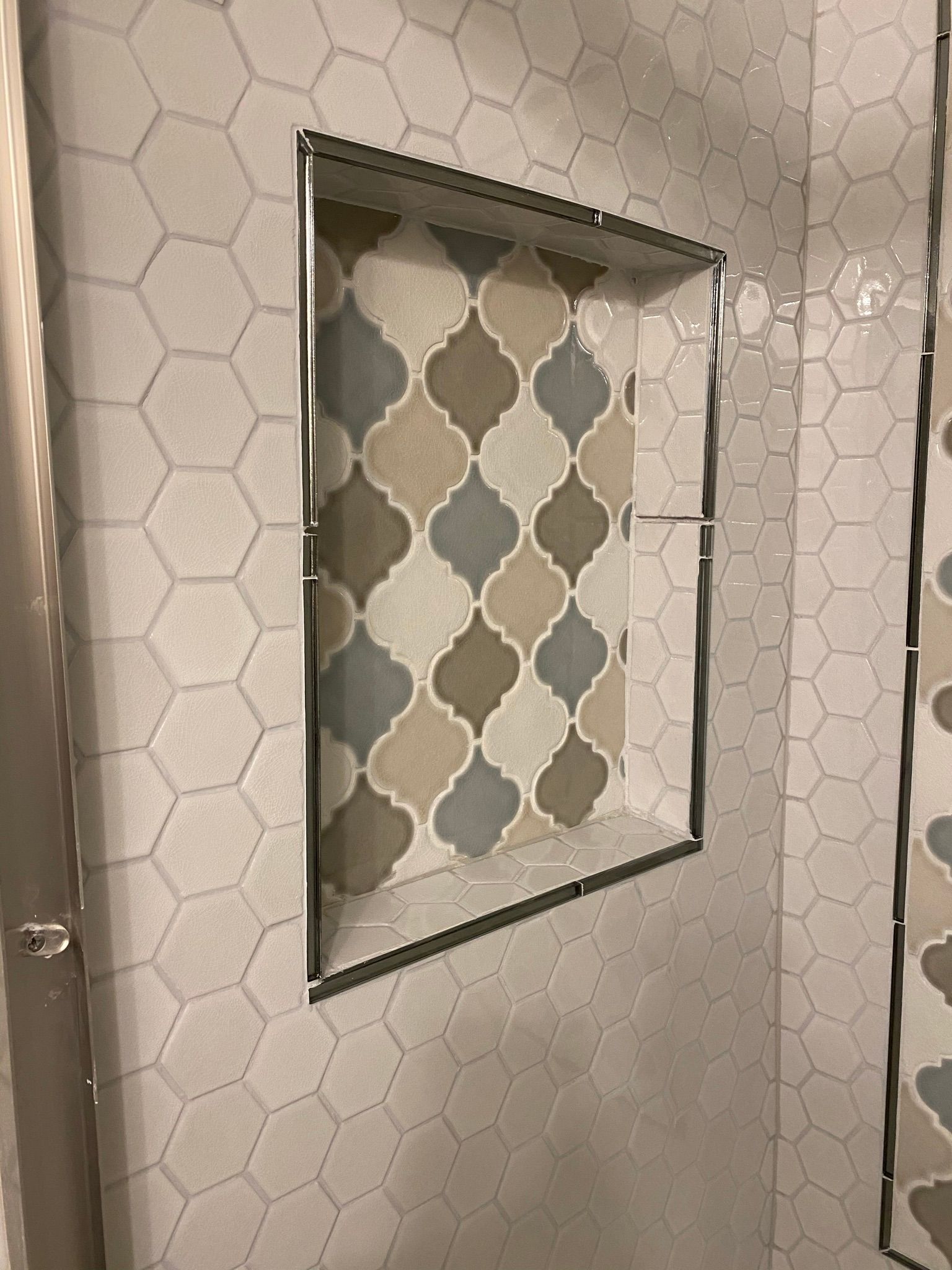 A shower niche with a geometric pattern on the wall.