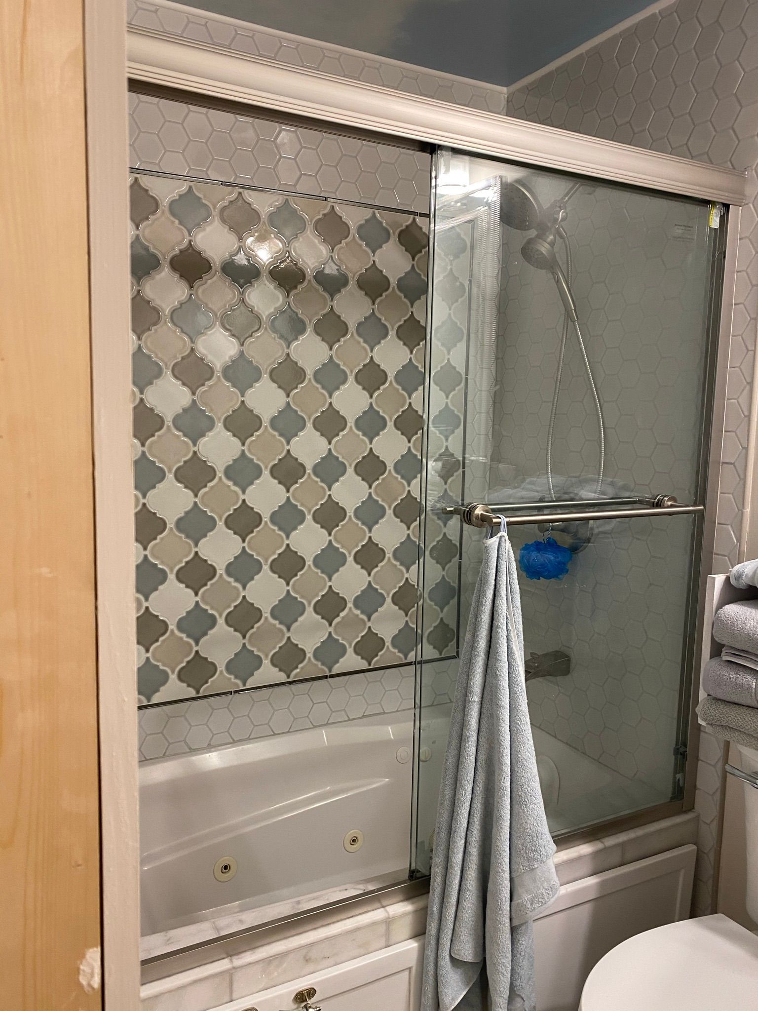 A bathroom with a sliding glass shower door and a bathtub