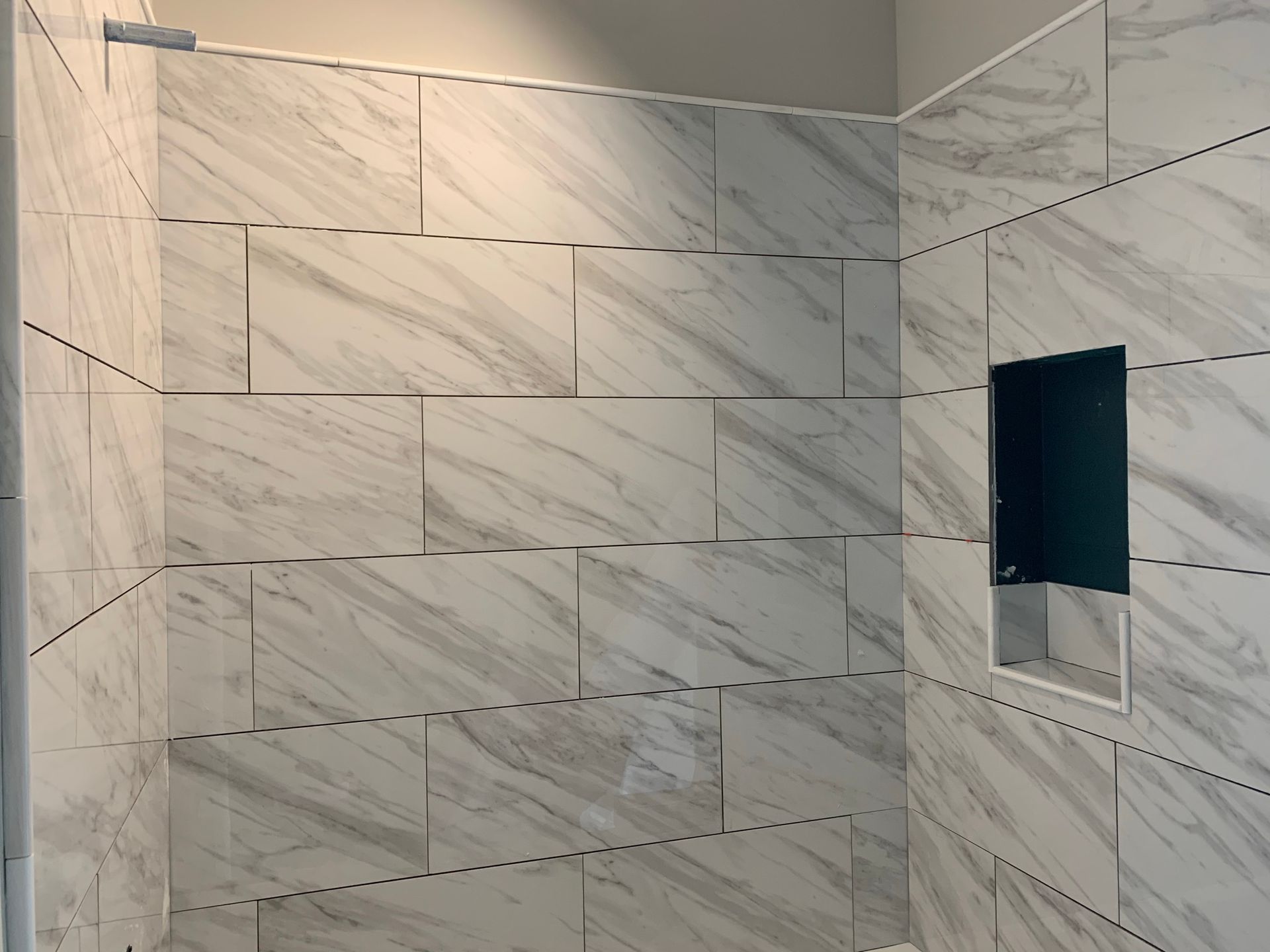 A bathroom with marble tiles and a shower stall