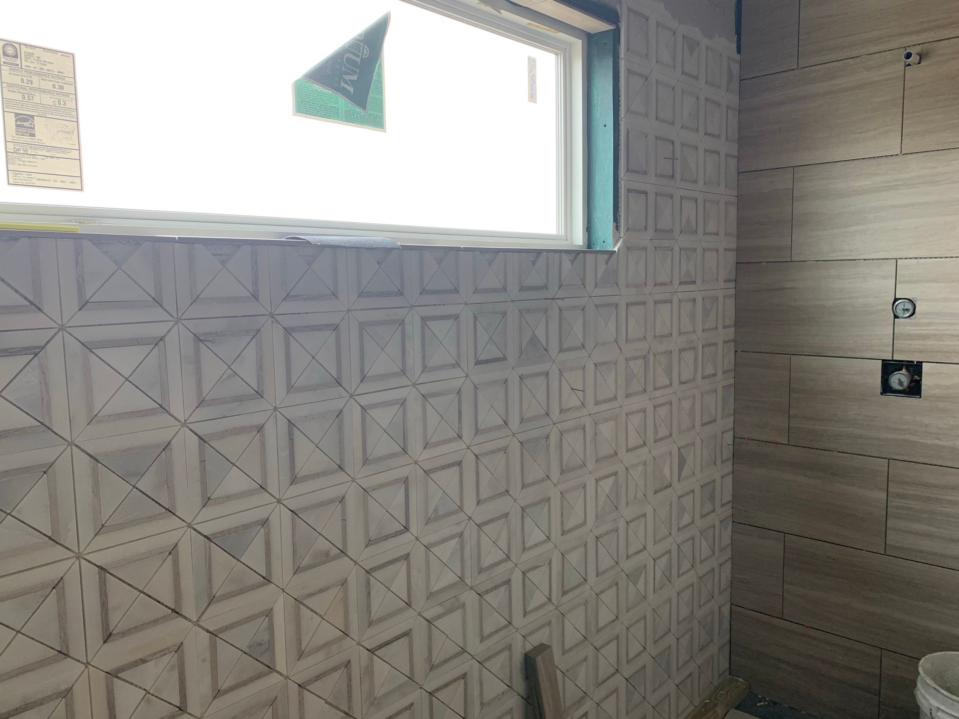 A bathroom with a geometric pattern on the wall and a window