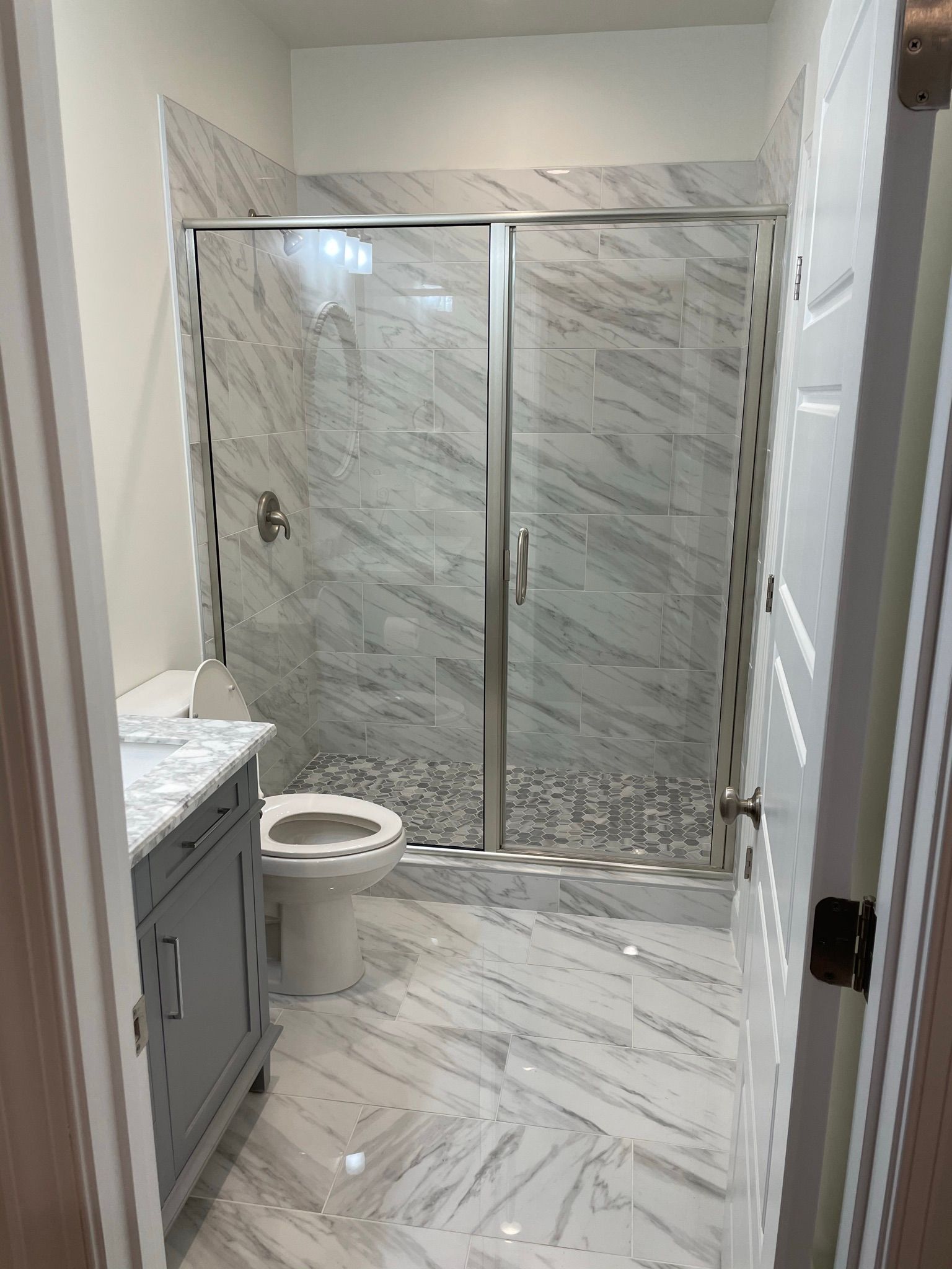 A bathroom with a toilet , sink and shower.